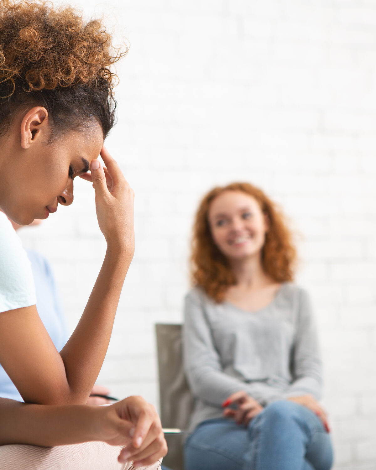 A small group of adults sitting in a circle in a softly lit therapy session.