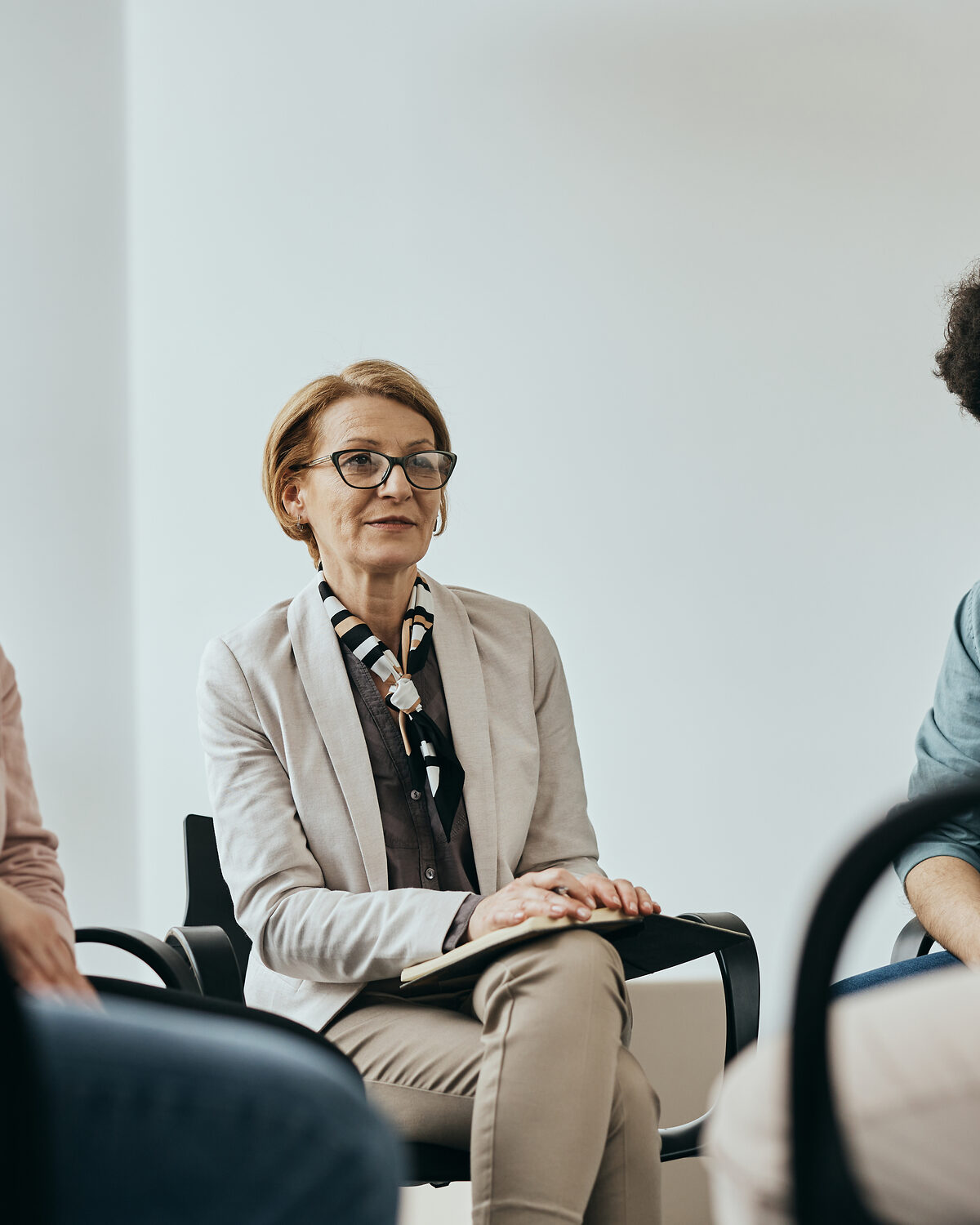 A clinician sitting attentively in a quiet, warmly lit office during a clinical session.
