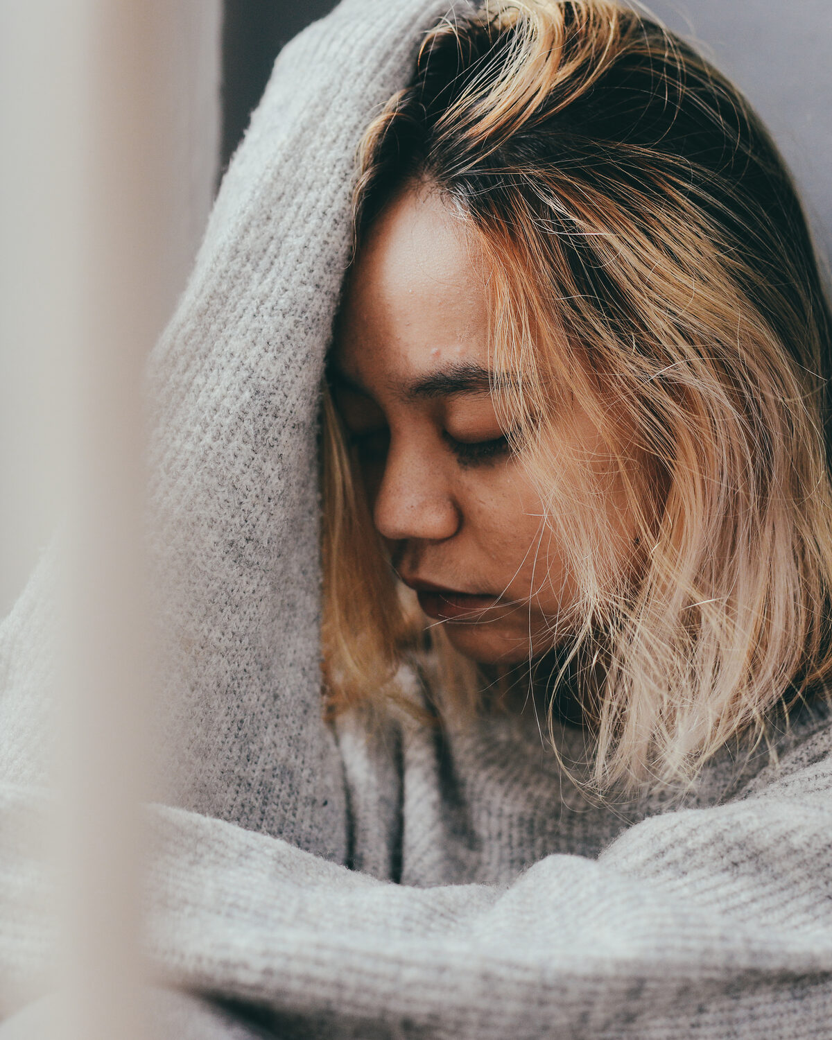 A young woman with her hands pressed to her face, looking distressed.