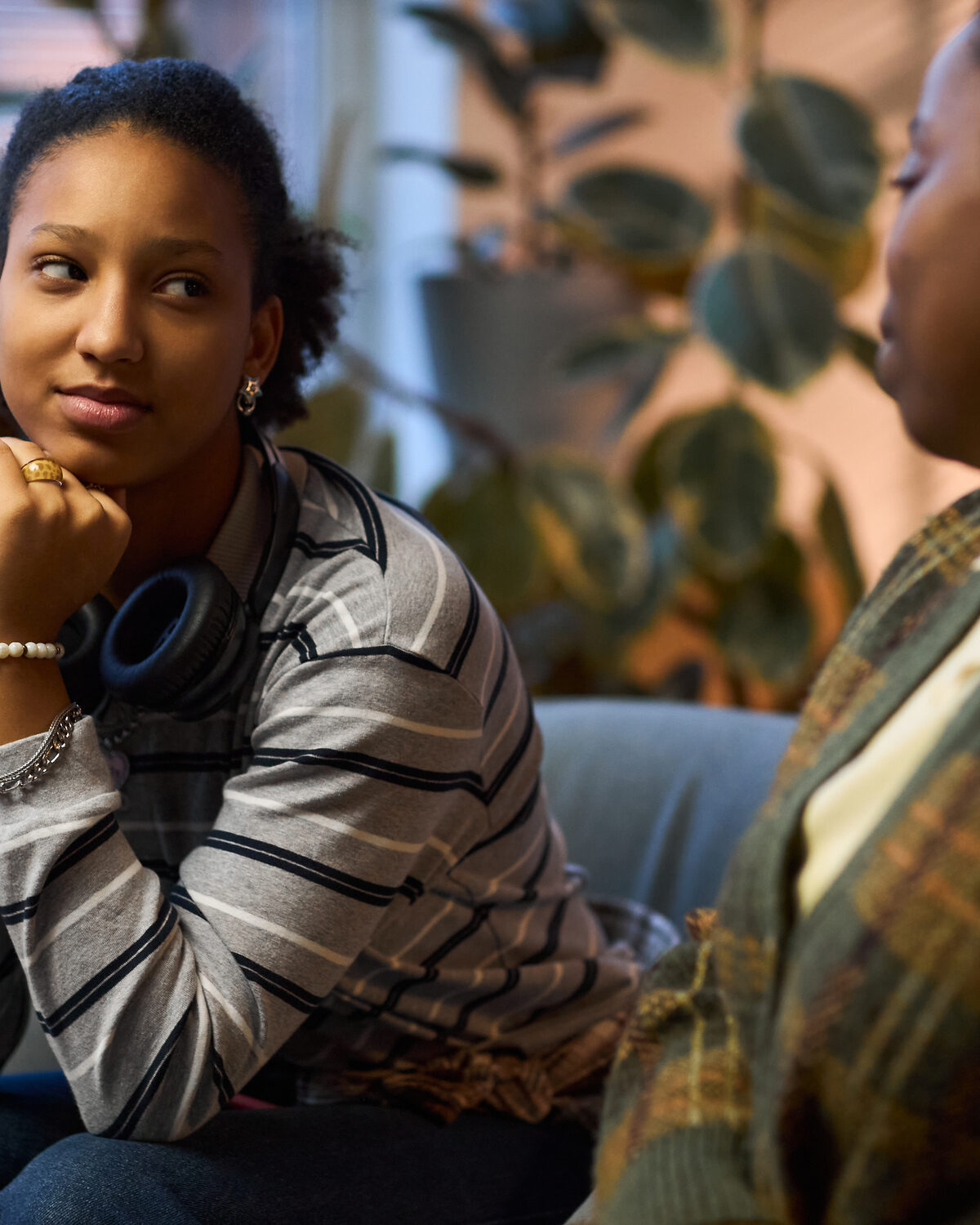 A young person and an older adult sitting and talking in a quiet, soft-lit home setting.