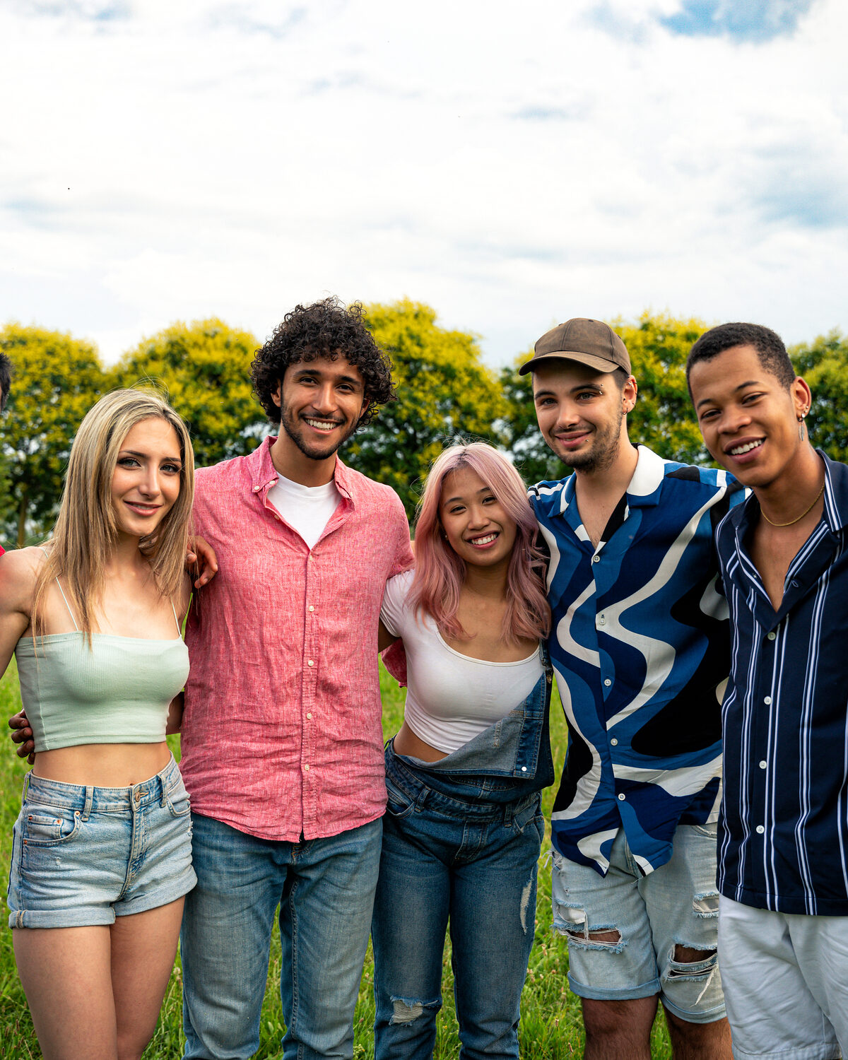A diverse group of teenagers spending time outdoors together in a park-like setting.