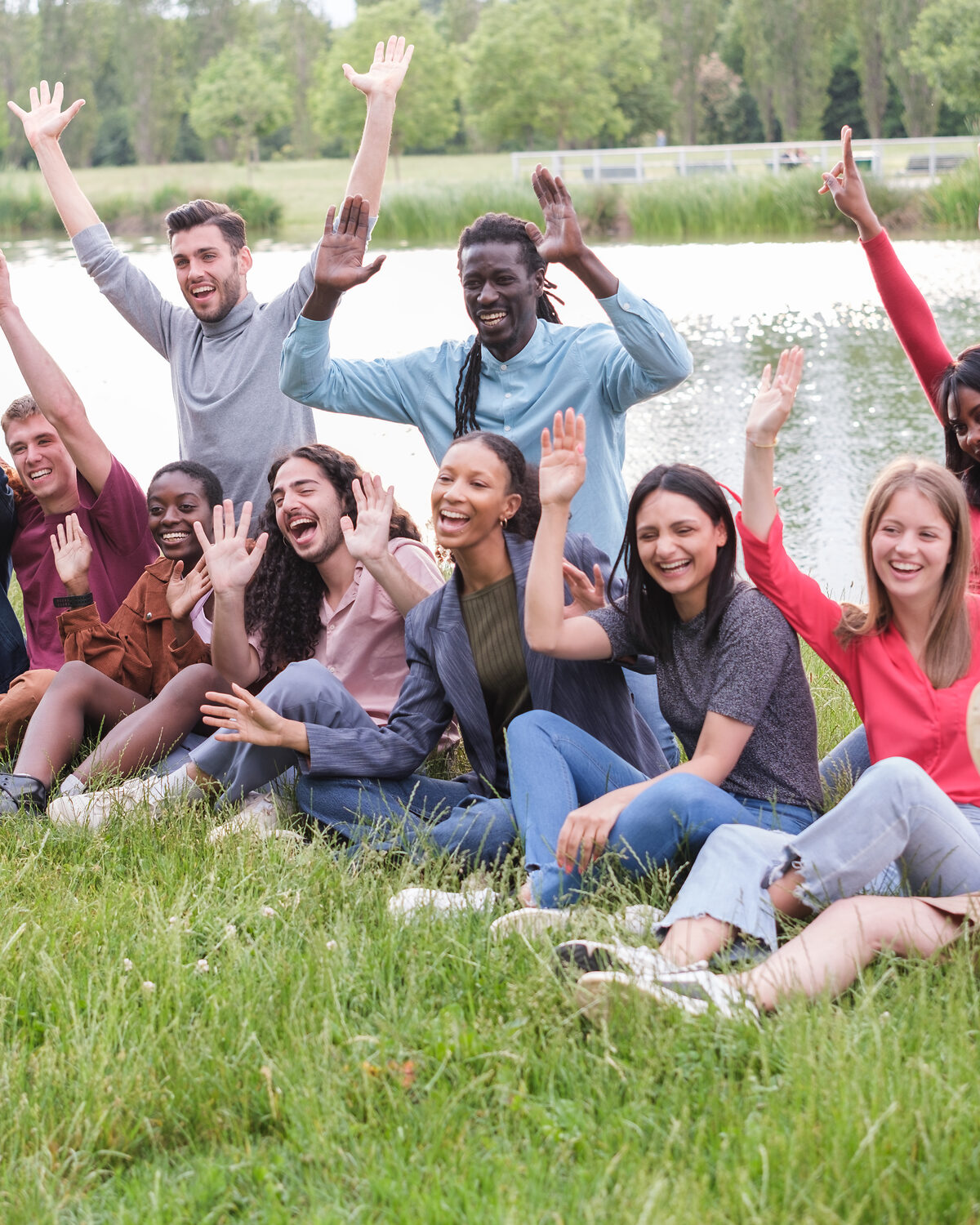 Young adults sitting together near a peaceful lake at sunset.